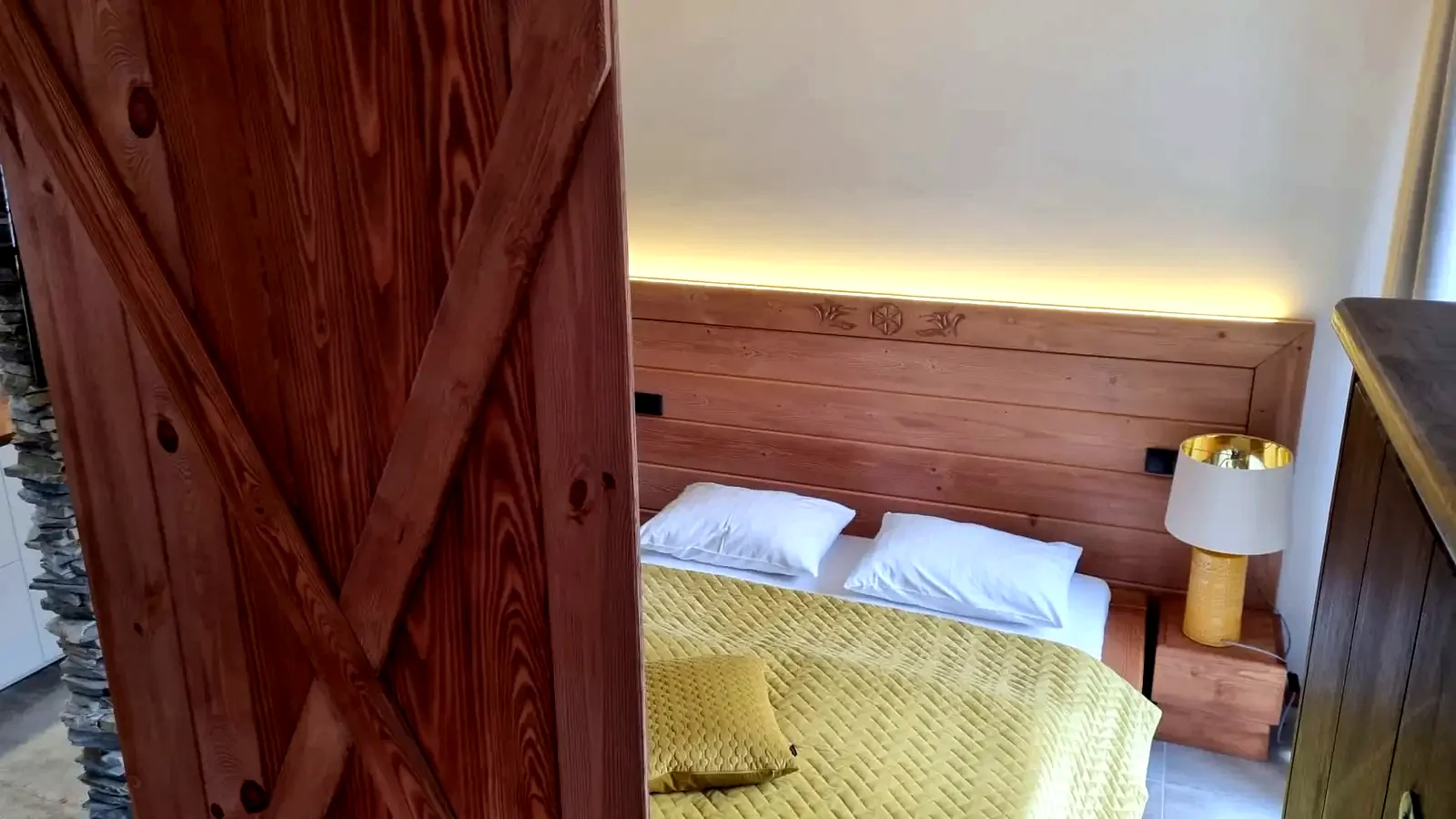 Sypialnia Apartamentu 1 z drewnianym zagłówkiem i ciepłym oświetleniem