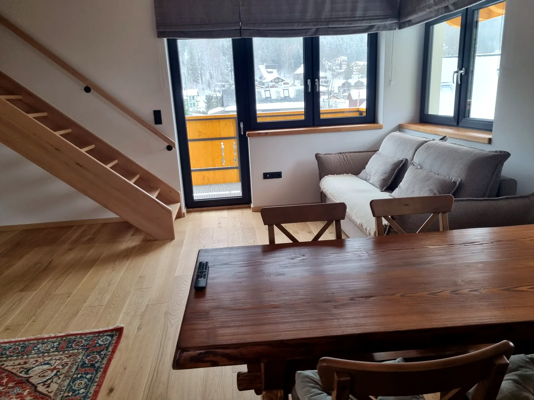 Strefa dzienna Apartamentu 4 z sofą, stołem i wyjściem na balkon